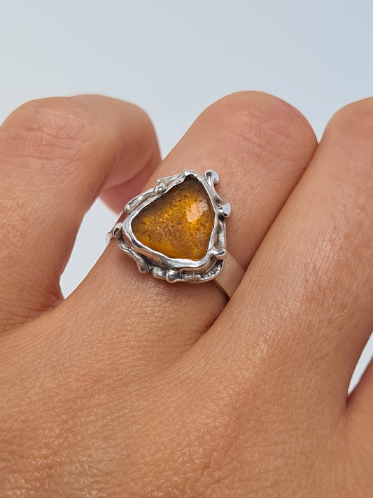 This unique silver ring is inspired by the organic shapes found in the sea. The amber sea gem is nestled in a sterling silver bezel set upon a thick band. Handmade with sustainability in mind this piece is made from 100% recycled silver.