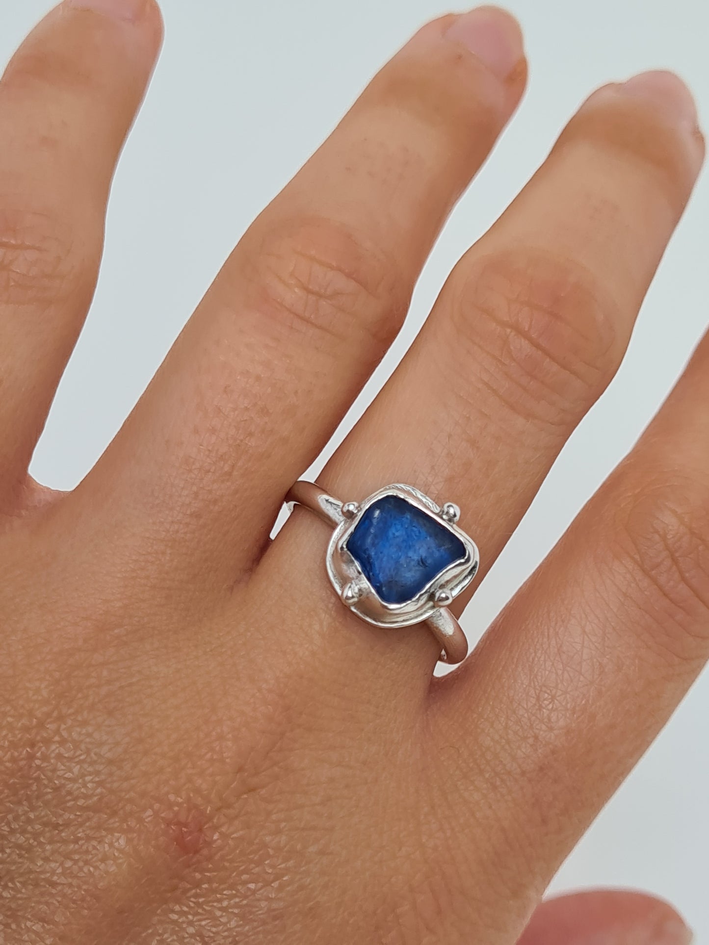 This vibrant royal blue sea gem is nestled in a sterling silver bezel with subtle embellishments and set upon an elegant D shaped band. Crafted with sustainability in mind this silver ring is handmade from 100% recycled silver.