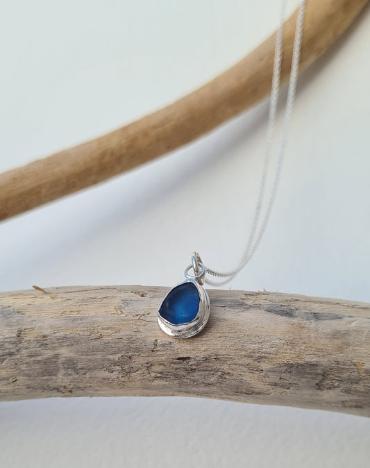 This bright little ocean blue piece of sea glass is nestled in a sterling silver bezel on a delicate silver cable chain. Handmade with sustainability in mind this silver necklace is made from 100% recycled silver.