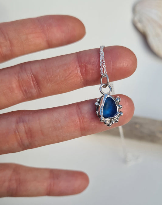 This unique pendant is inspired by the organic shapes found in the sea. The ocean blue sea glass is nestled in a sterling silver bezel on a delicate silver cable chain. Handmade with sustainability in mind this necklace is made from 100% recycled silver.  This piece of sea glass was found in West Cork, Ireland. A fragment of our beloved Irish coastline forever preserved in silver.
