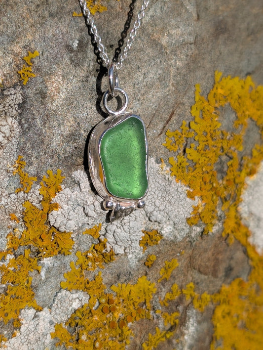 Green pendant necklace on a lichen-covered stone